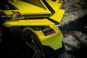 A close up of the rear end of a yellow car.
