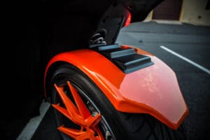 A close up of the rear wheel on an orange motorcycle.