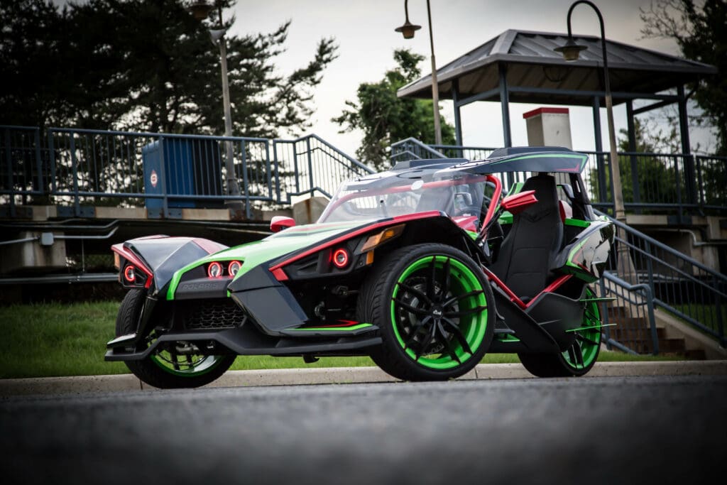 A green and black car parked on the side of the road.