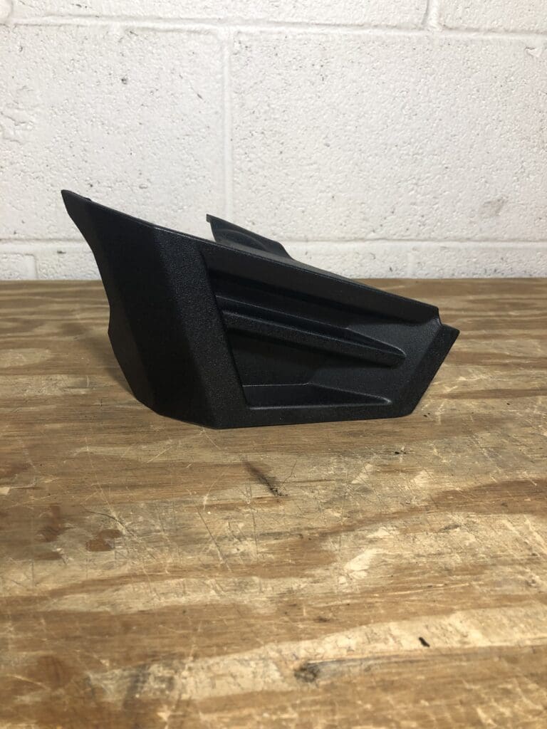 A black plastic object sitting on top of a wooden floor.
