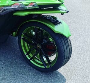 A close up of the front wheel on a green motorcycle.