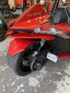 A red motorcycle parked in a garage with its front tire.