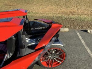 A red car with some blue rims on the road