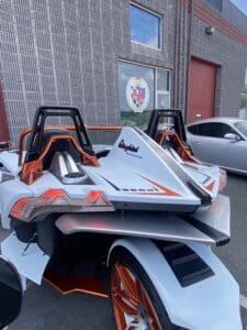 A close up of the back end of an orange and white car.