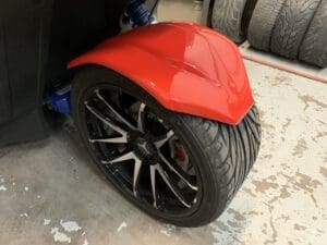 A red motorcycle tire on the ground with black rims.