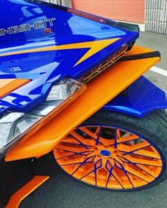 A close up of the wheel on a blue and orange car