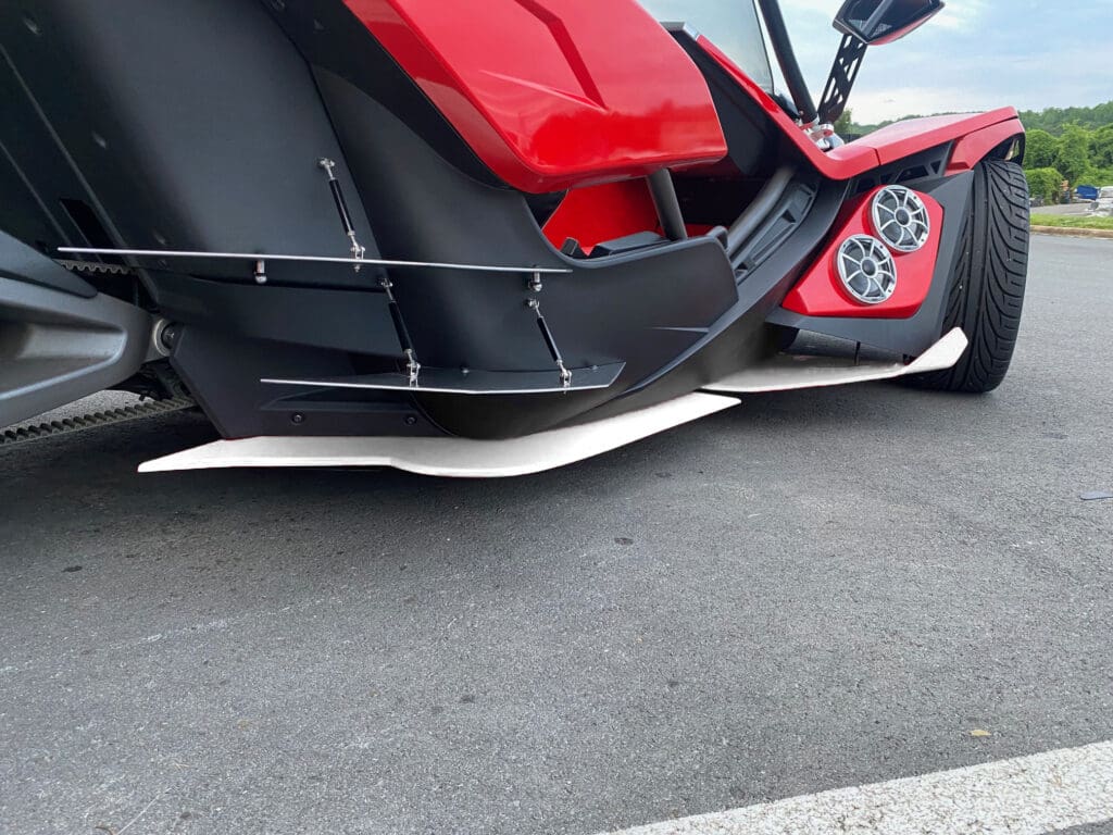 Red three-wheeled vehicle with side skirts.