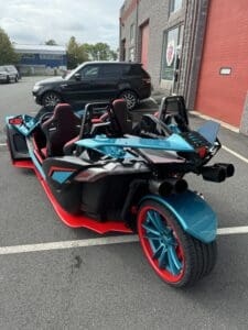 Blue and red three-wheeled vehicle parked.